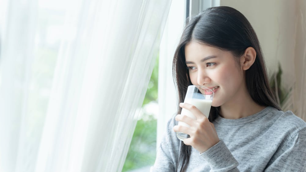 靠着窗的女人正在饮用豆浆